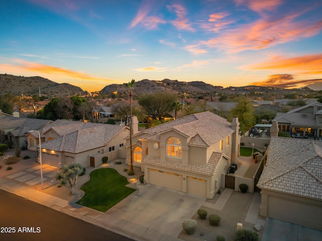 view of front of home with concrete driveway, a residential view, an attached garage, a mountain view, and stucco siding