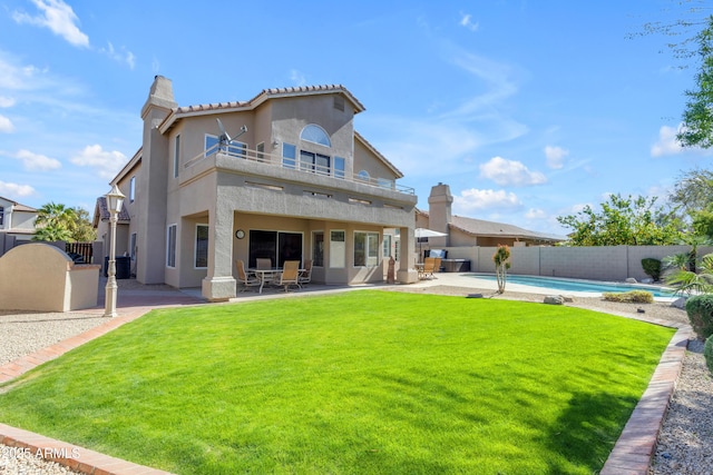 rear view of property featuring a yard, stucco siding, a patio area, a balcony, and a fenced backyard