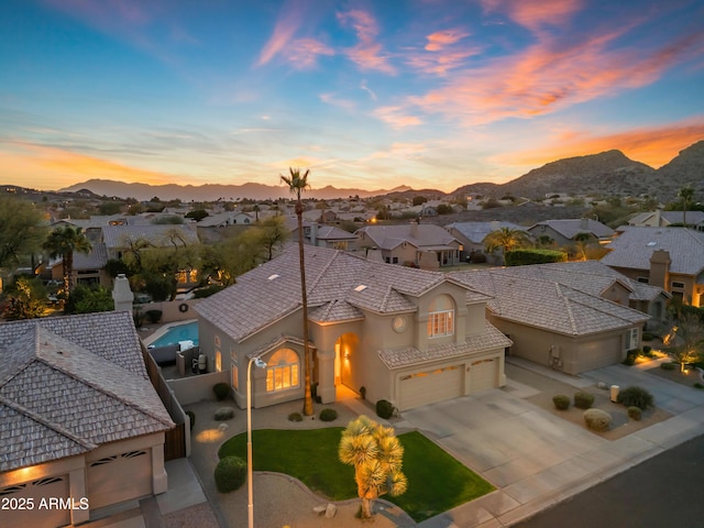 mediterranean / spanish-style home with stucco siding, a mountain view, fence, a residential view, and driveway