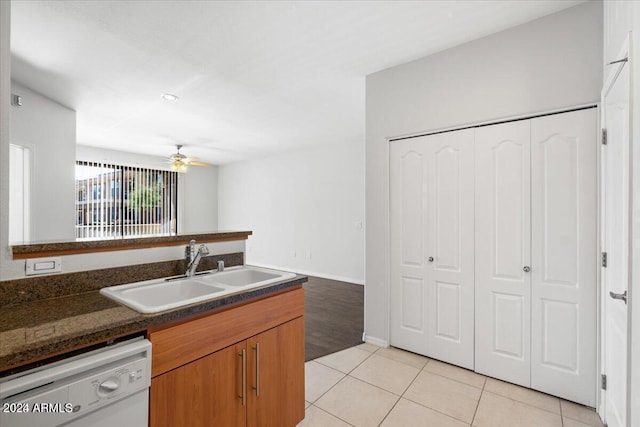 kitchen with dark stone counters, white dishwasher, ceiling fan, sink, and light tile patterned floors