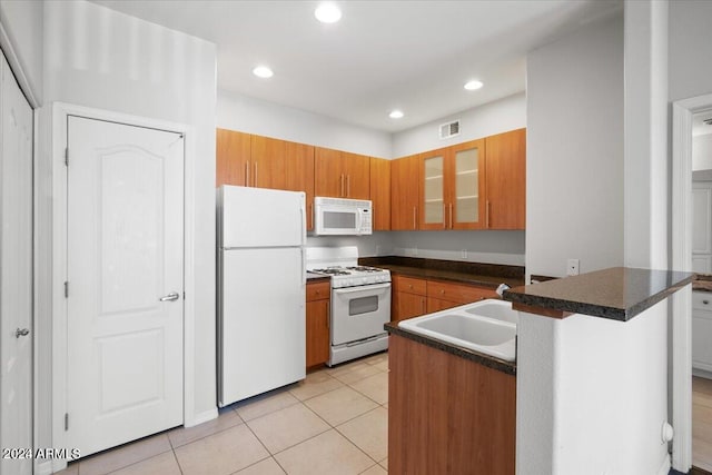 kitchen with kitchen peninsula, sink, light tile patterned floors, and white appliances