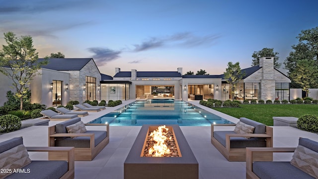 pool at dusk featuring a patio, a yard, and a fire pit