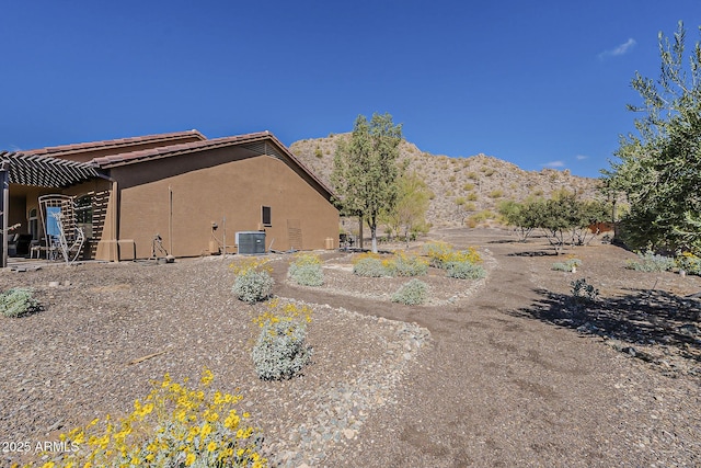 rear view of property featuring cooling unit, a mountain view, and stucco siding