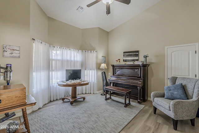 living area featuring visible vents, ceiling fan, wood finished floors, high vaulted ceiling, and baseboards