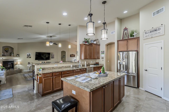 kitchen featuring arched walkways, visible vents, appliances with stainless steel finishes, open floor plan, and a sink