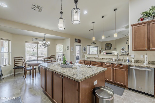 kitchen with a center island, visible vents, stainless steel dishwasher, a sink, and light stone countertops