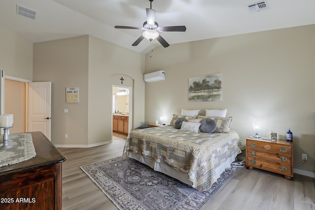 bedroom with a wall unit AC, light wood-style flooring, visible vents, and baseboards