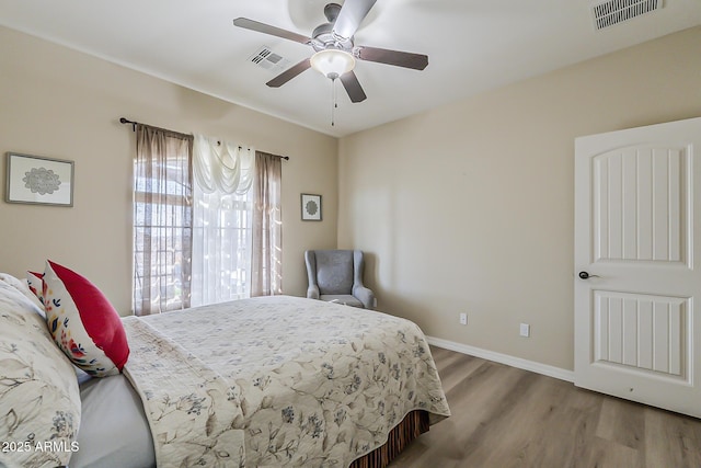 bedroom featuring a ceiling fan, baseboards, visible vents, and wood finished floors