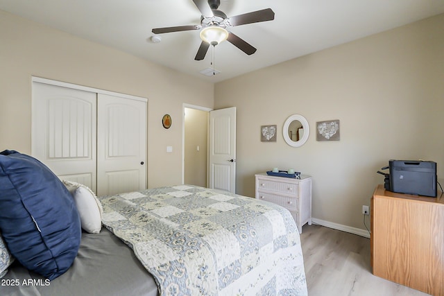 bedroom featuring light wood-style floors, ceiling fan, baseboards, and a closet