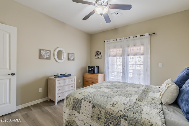 bedroom featuring light wood finished floors, baseboards, visible vents, and a ceiling fan