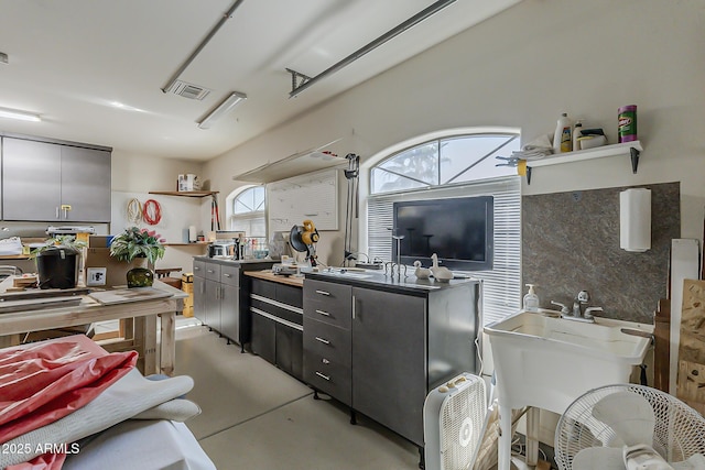 kitchen featuring finished concrete flooring, open shelves, a sink, and visible vents