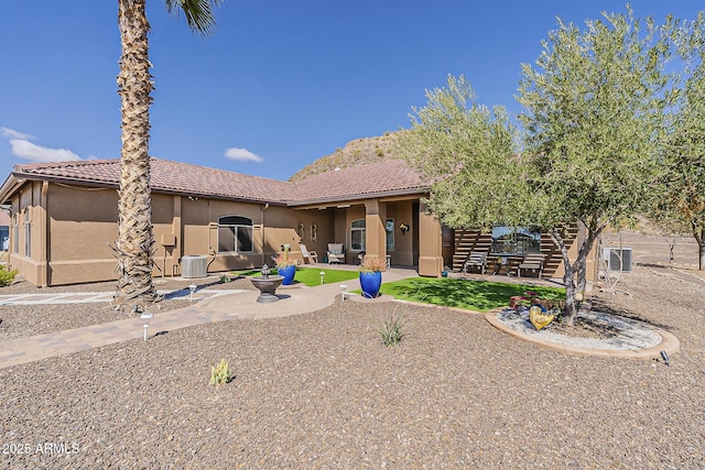 rear view of property featuring stucco siding, a tile roof, central AC, and a patio