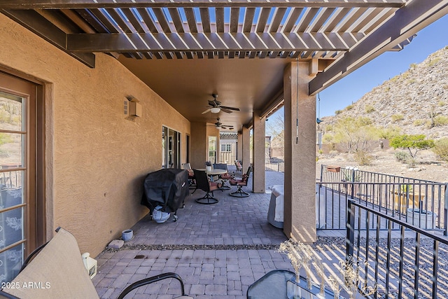 view of patio / terrace featuring area for grilling, fence, a ceiling fan, and a pergola