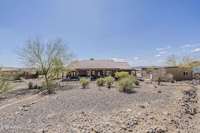 rear view of house featuring a patio area and a tile roof