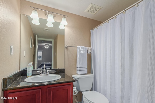 bathroom with vanity, a textured ceiling, a shower with shower curtain, ceiling fan, and toilet