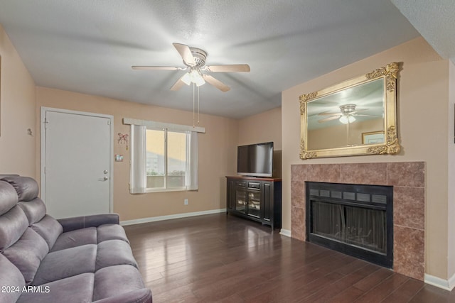 living room featuring ceiling fan, a textured ceiling, a fireplace, and dark hardwood / wood-style floors