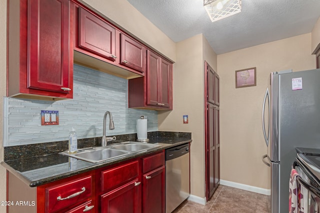 kitchen with a textured ceiling, sink, decorative backsplash, appliances with stainless steel finishes, and light tile patterned floors