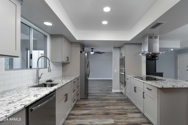 kitchen featuring appliances with stainless steel finishes, light stone counters, island range hood, ceiling fan, and sink