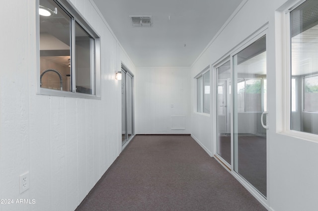 hallway featuring dark colored carpet and crown molding