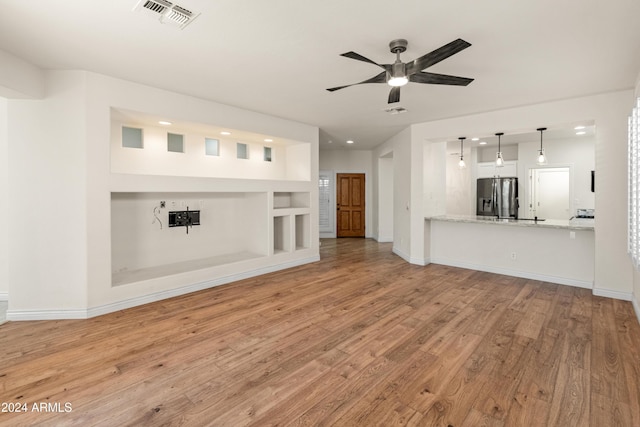 unfurnished living room featuring ceiling fan, built in features, and light hardwood / wood-style flooring