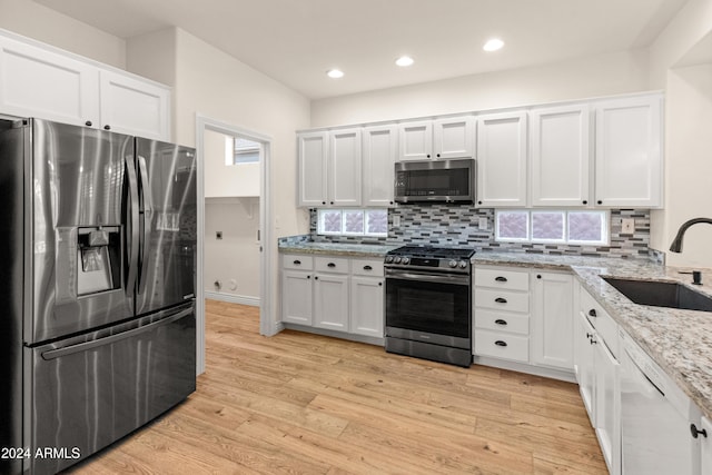 kitchen featuring white cabinets, sink, decorative backsplash, light hardwood / wood-style floors, and stainless steel appliances