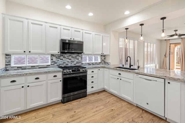 kitchen with appliances with stainless steel finishes, light wood-type flooring, sink, decorative light fixtures, and white cabinets