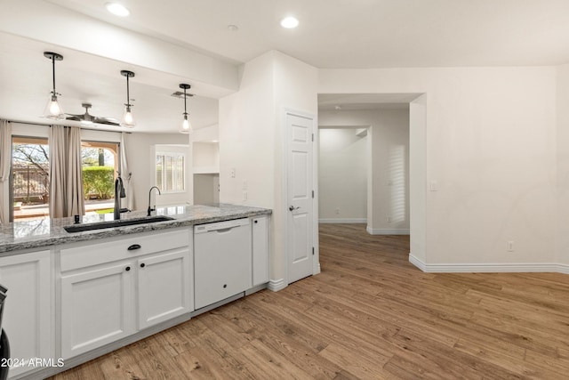 kitchen featuring white dishwasher, white cabinets, sink, light hardwood / wood-style floors, and light stone counters