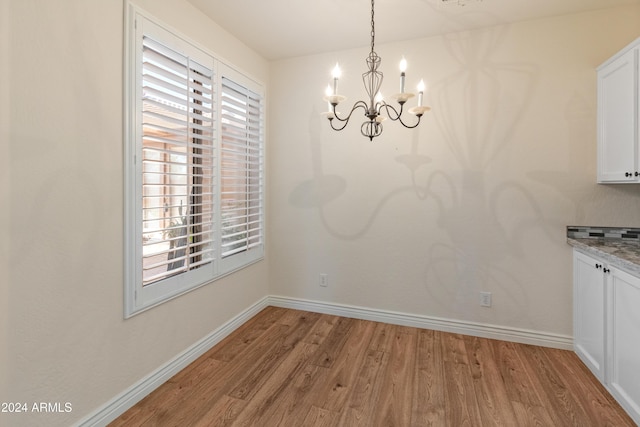 unfurnished dining area with a chandelier and light hardwood / wood-style flooring