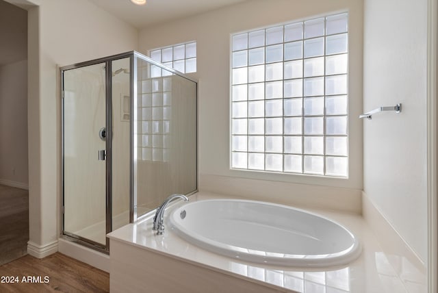 bathroom featuring plus walk in shower and wood-type flooring