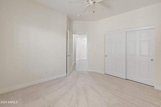 unfurnished bedroom featuring light carpet, a closet, and ceiling fan