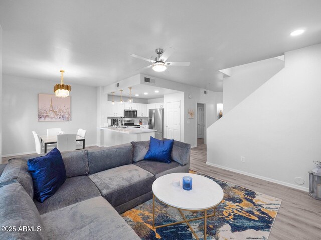 14000 N 94th St Unit 1008, Scottsdale, AZ 85260 - living room featuring baseboards, light wood finished floors, visible vents, and ceiling fan with notable chandelier