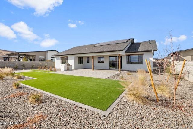 back of property featuring a yard, a patio area, and solar panels