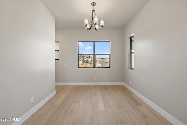 empty room with an inviting chandelier and light hardwood / wood-style flooring