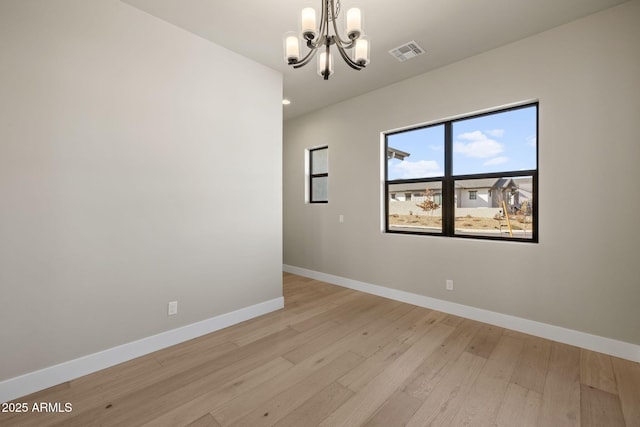 empty room with a notable chandelier and light hardwood / wood-style flooring