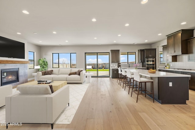 living room with a tile fireplace and light hardwood / wood-style flooring