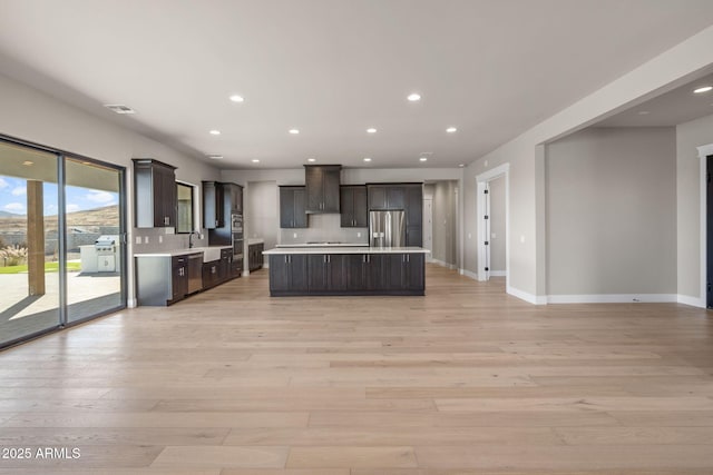 kitchen featuring sink, light hardwood / wood-style flooring, stainless steel appliances, a center island, and dark brown cabinetry