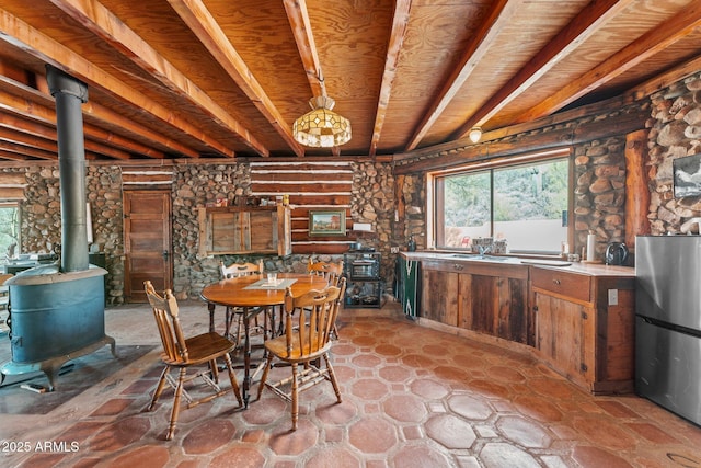 dining space with beamed ceiling and a wood stove