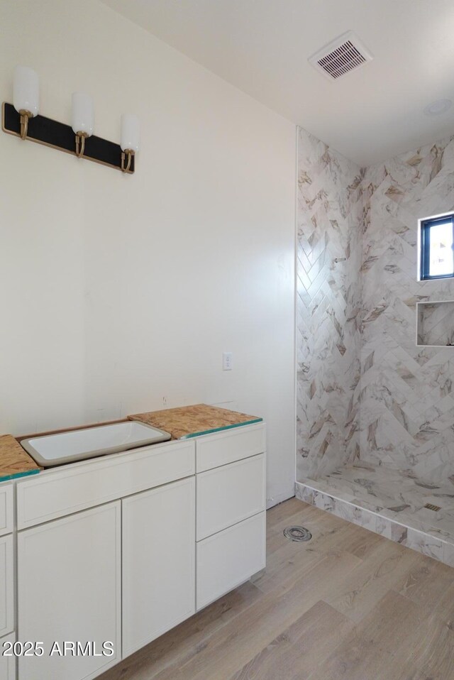 full bathroom featuring a marble finish shower, visible vents, and wood finished floors