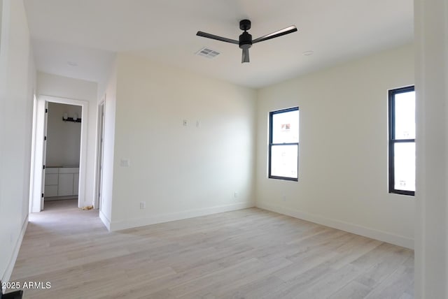 spare room with light wood finished floors, visible vents, a ceiling fan, and baseboards