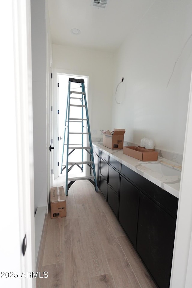 hall with visible vents, light wood-type flooring, and a sink