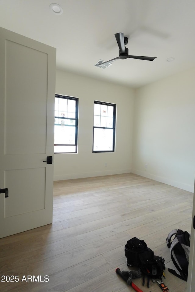 spare room with visible vents, light wood-style floors, baseboards, and ceiling fan