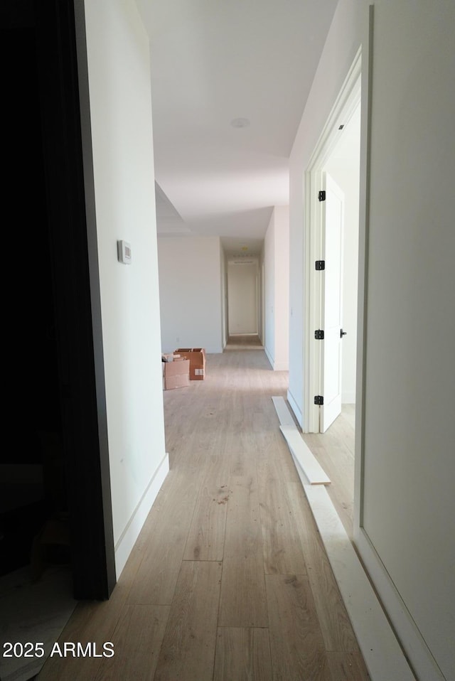 corridor with baseboards and light wood-style flooring