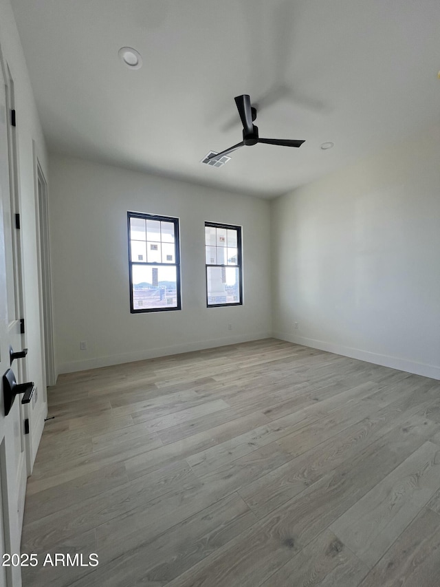 spare room with a ceiling fan, baseboards, visible vents, and light wood finished floors