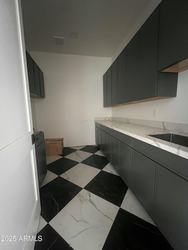 kitchen featuring light stone counters, dark cabinets, and tile patterned floors