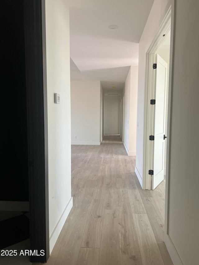 corridor with light wood-style floors and baseboards