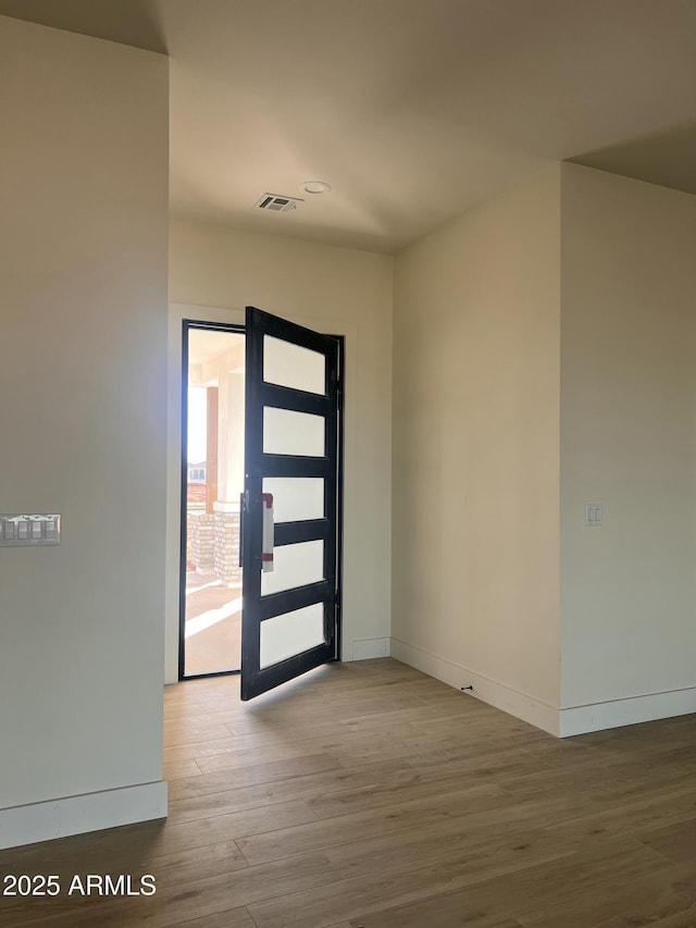 entrance foyer with wood finished floors, visible vents, and baseboards