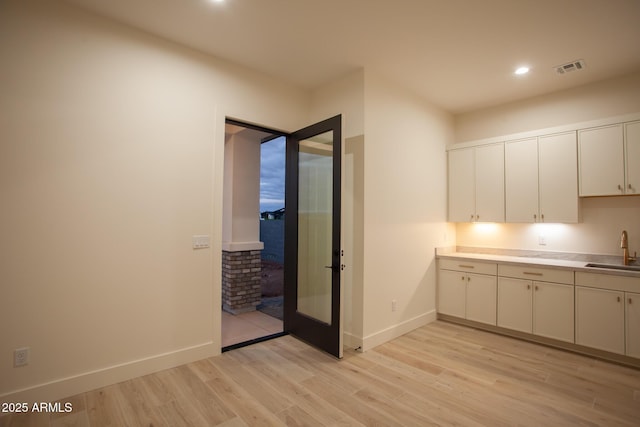 kitchen featuring light wood-type flooring, a sink, recessed lighting, light countertops, and baseboards