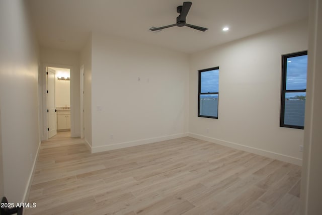 empty room with a ceiling fan, light wood-style floors, and baseboards