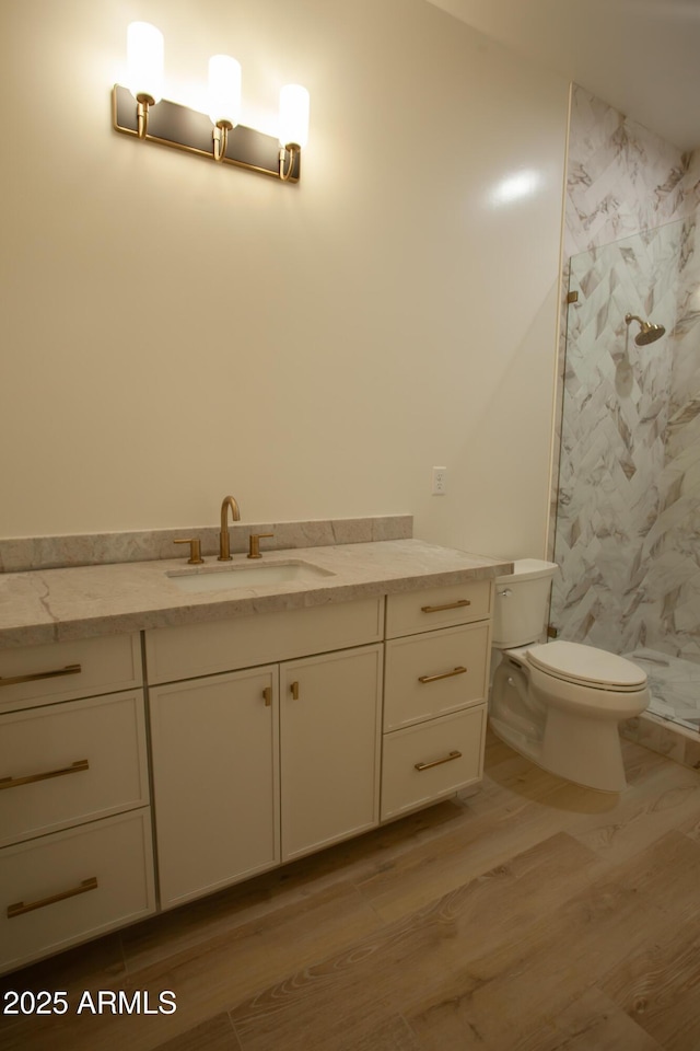 full bathroom with wood finished floors, toilet, a stall shower, and vanity