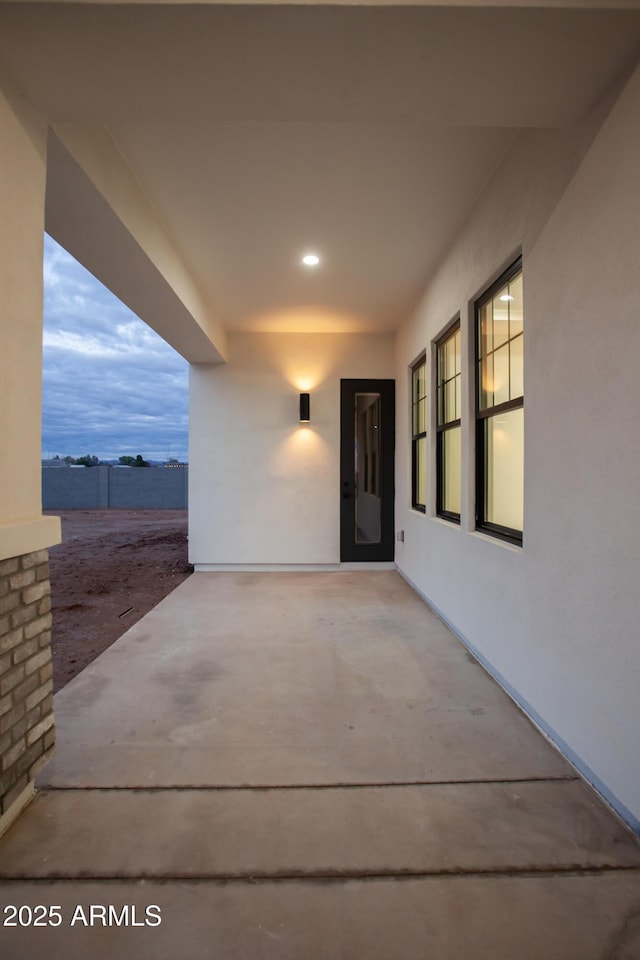 view of exterior entry with stucco siding and a patio